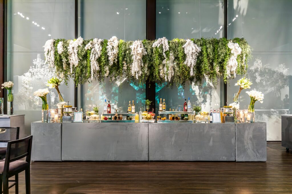 Stylish event bar with hanging greenery and floral arrangements, perfect for a sophisticated setting.