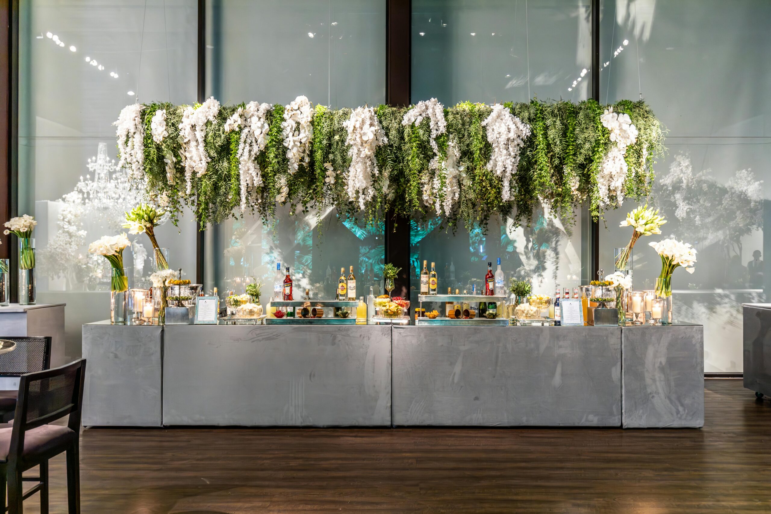 Stylish event bar with hanging greenery and floral arrangements, perfect for a sophisticated setting.