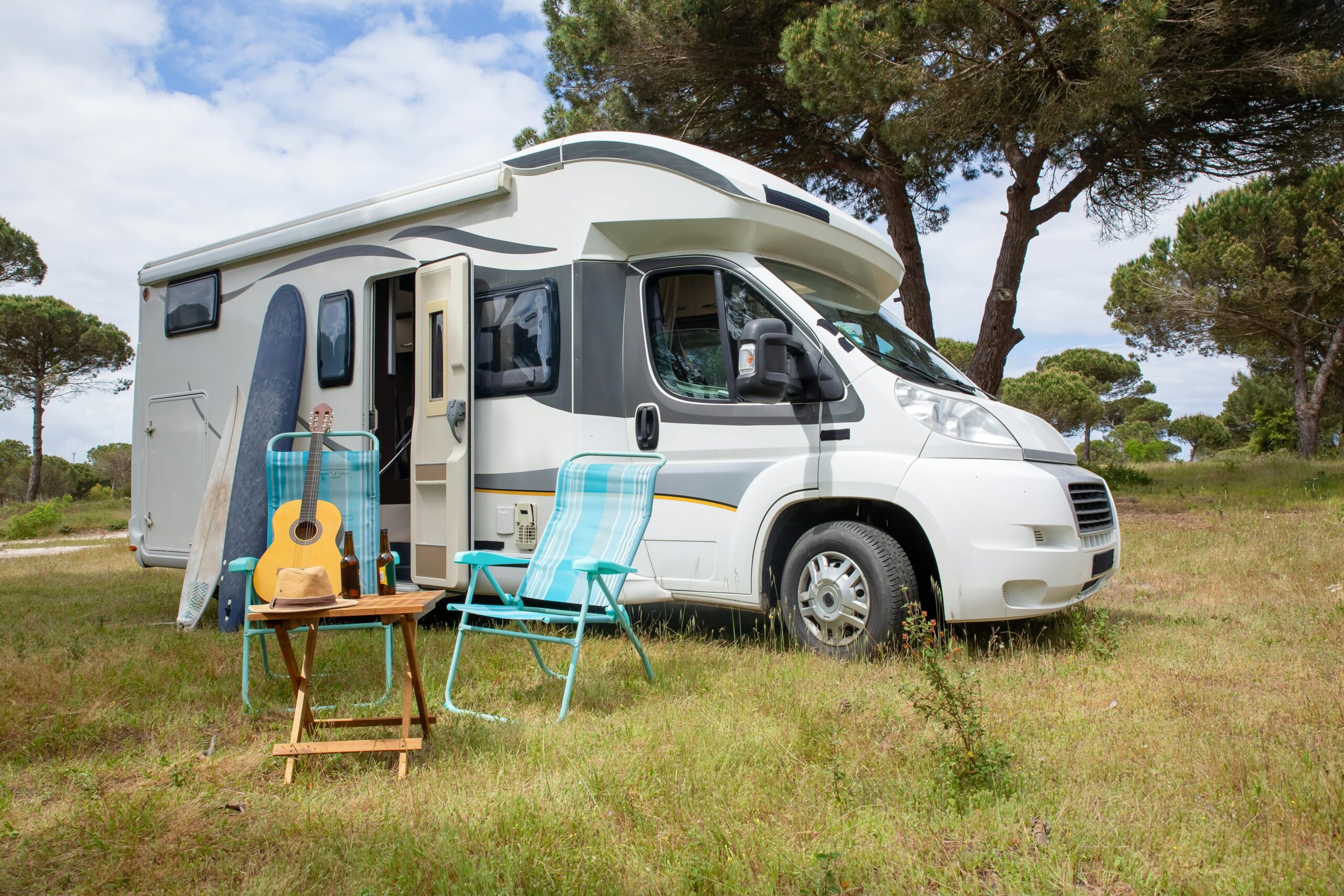 Explore the outdoor lifestyle with an RV, surfboards, and guitar in a serene Portuguese park.
